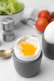 Photo of Soft boiled eggs in cups served on white table, closeup