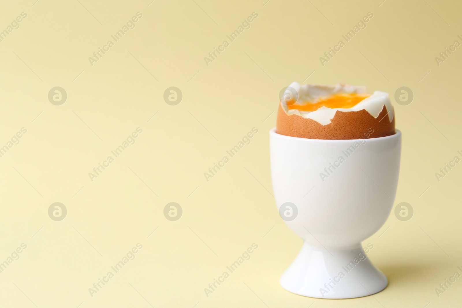 Photo of Soft boiled egg in eggcup on beige background, closeup. Space for text