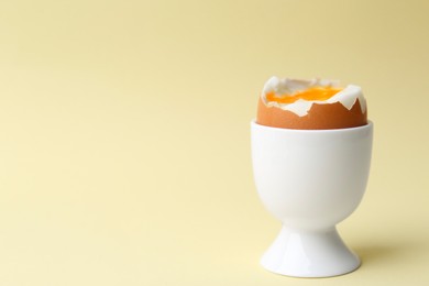 Soft boiled egg in eggcup on beige background, closeup. Space for text