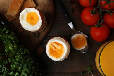 Photo of Soft boiled eggs, microgreens and tomatoes on wooden table, flat lay