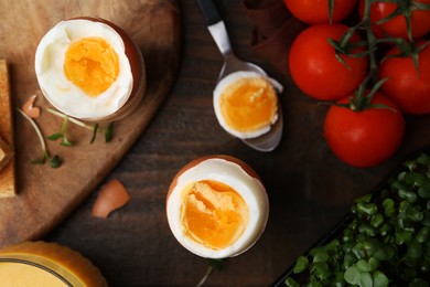 Photo of Soft boiled eggs, microgreens and tomatoes on wooden table, flat lay