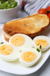 Photo of Hard boiled eggs with bread on light table, closeup