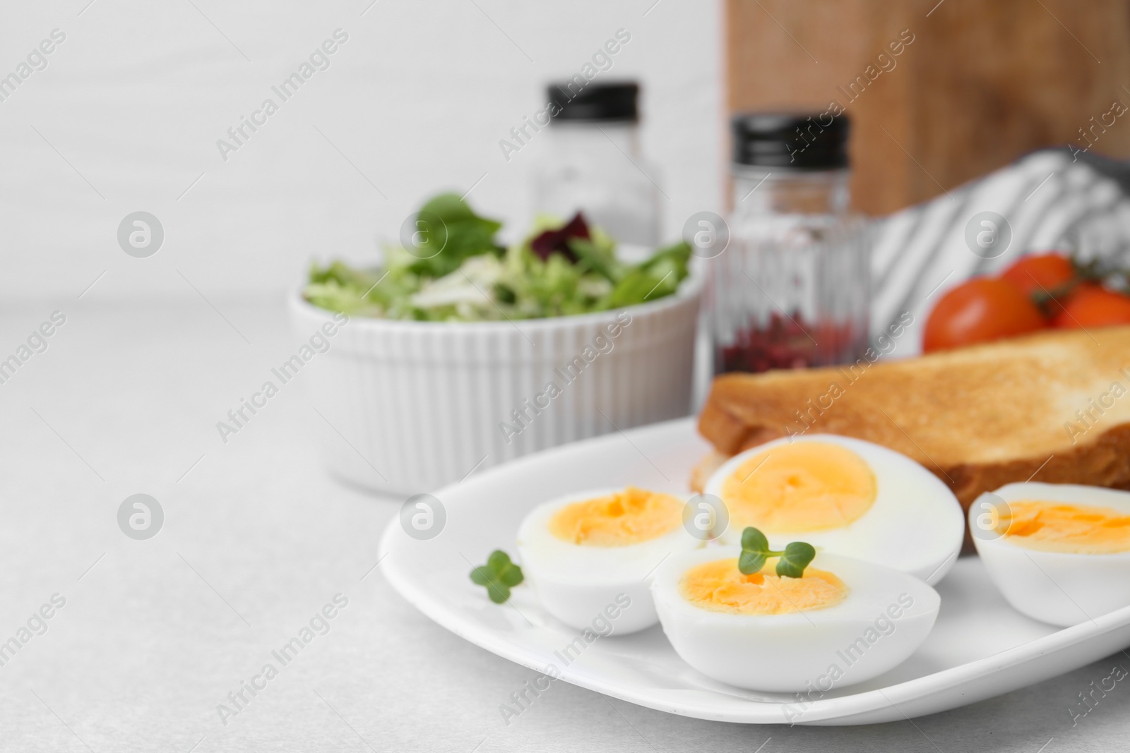 Photo of Hard boiled eggs with bread on light table, closeup. Space for text