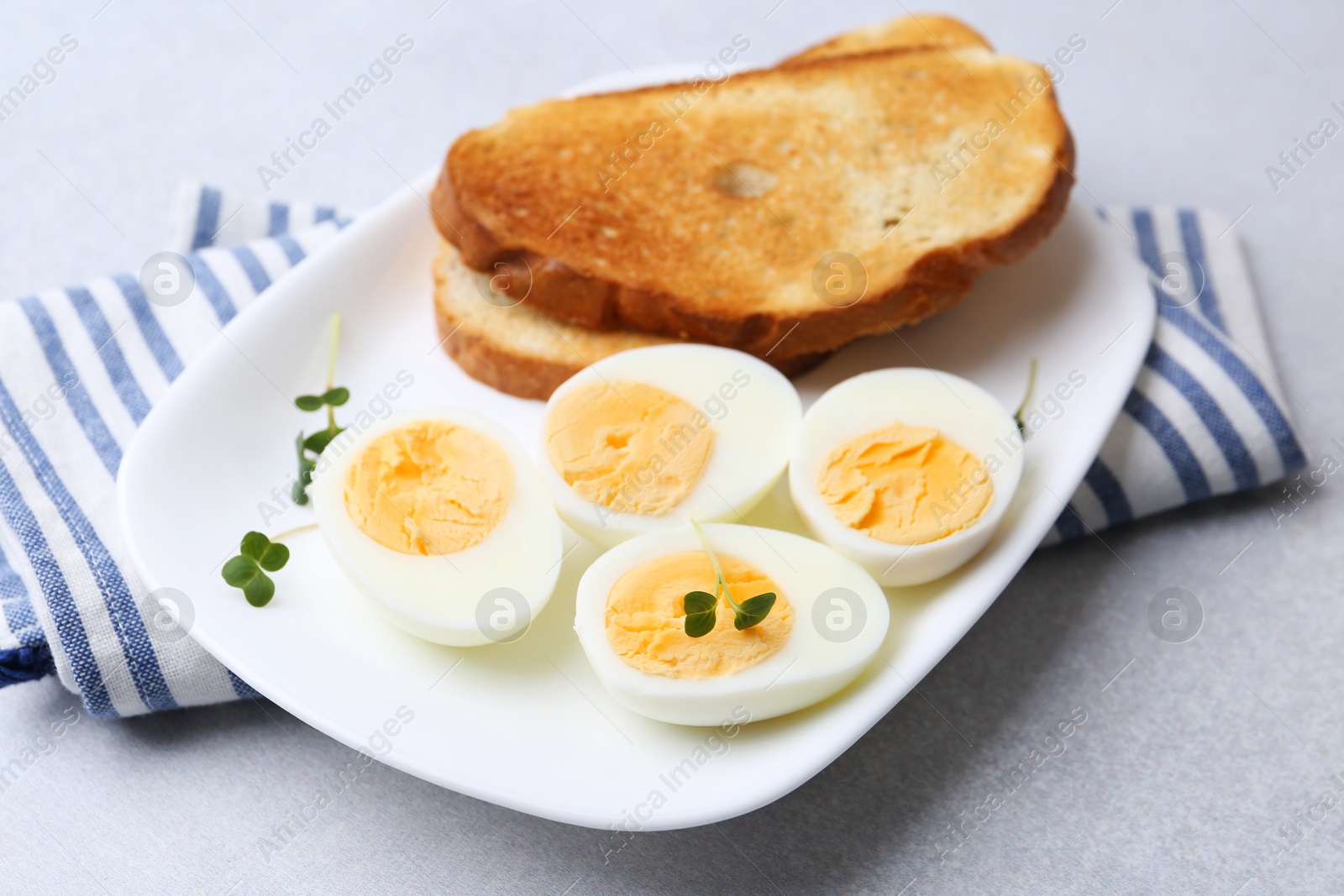 Photo of Hard boiled eggs with bread on light table, closeup