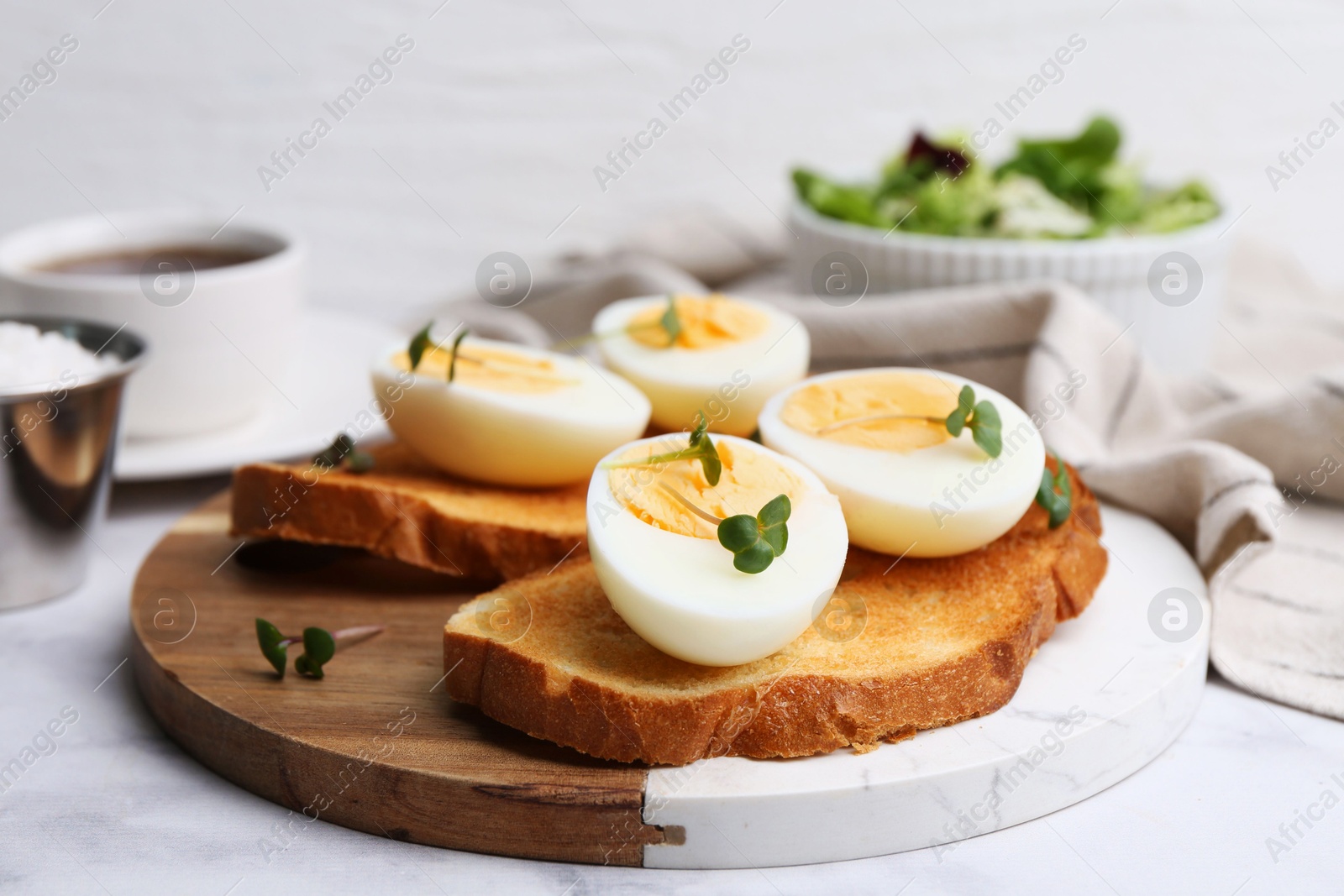 Photo of Sandwiches with hard boiled eggs on white marble table, closeup