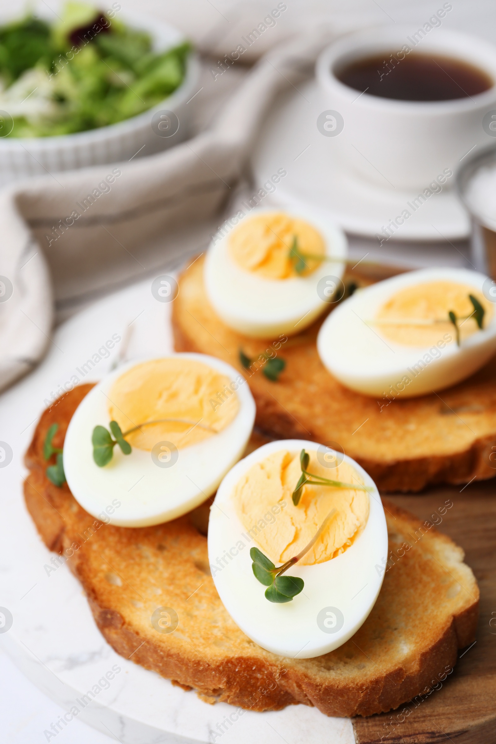 Photo of Sandwiches with hard boiled eggs on white table, closeup