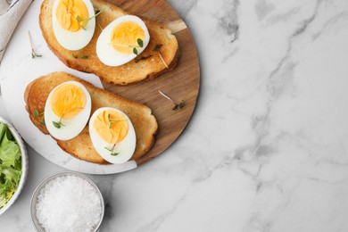 Photo of Sandwiches with hard boiled eggs on white marble table, flat lay. Space for text