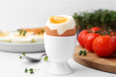 Photo of Soft boiled egg on white tiled table, closeup