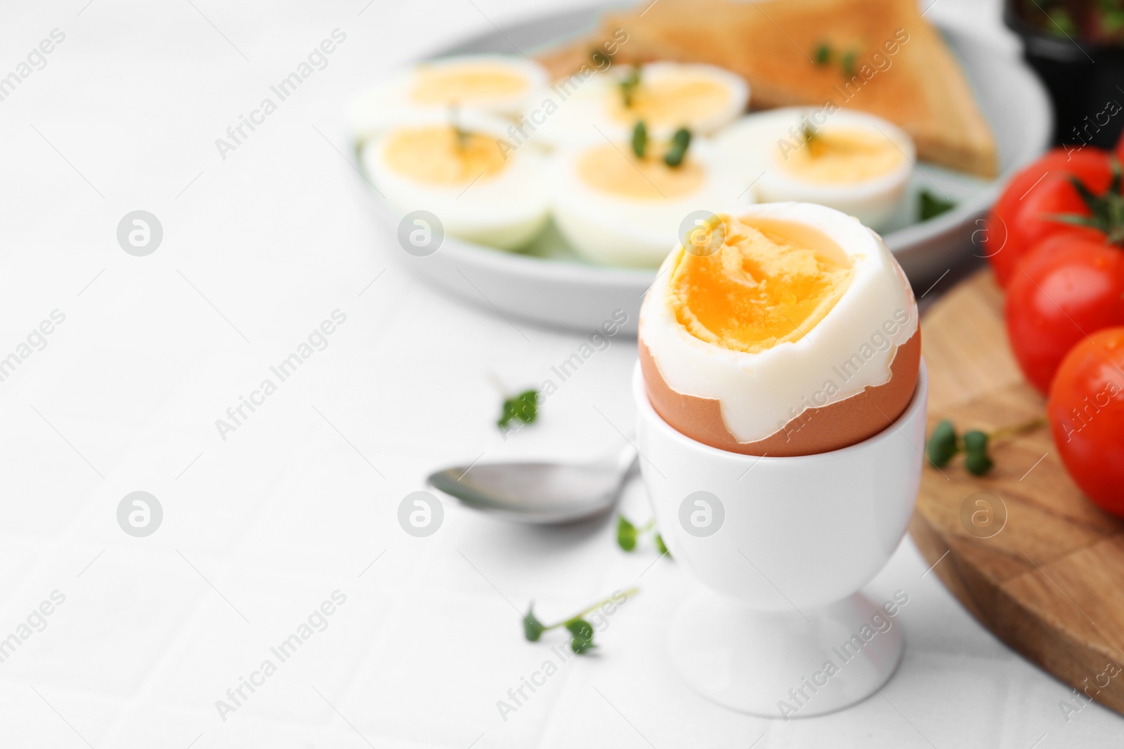 Photo of Soft boiled egg on white tiled table, closeup. Space for text