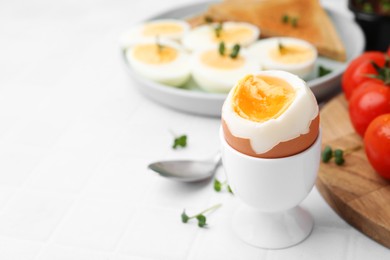 Photo of Soft boiled egg on white tiled table, closeup. Space for text