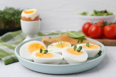 Photo of Cut hard boiled eggs with bread on white tiled table, closeup