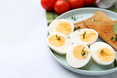 Photo of Cut hard boiled eggs with bread on white tiled table, closeup. Space for text