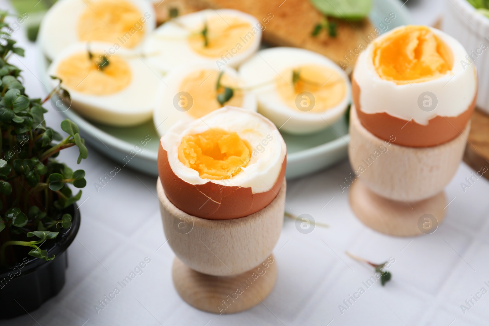 Photo of Many boiled eggs on white tiled table, selective focus