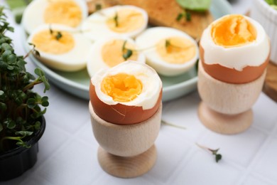 Photo of Many boiled eggs on white tiled table, selective focus