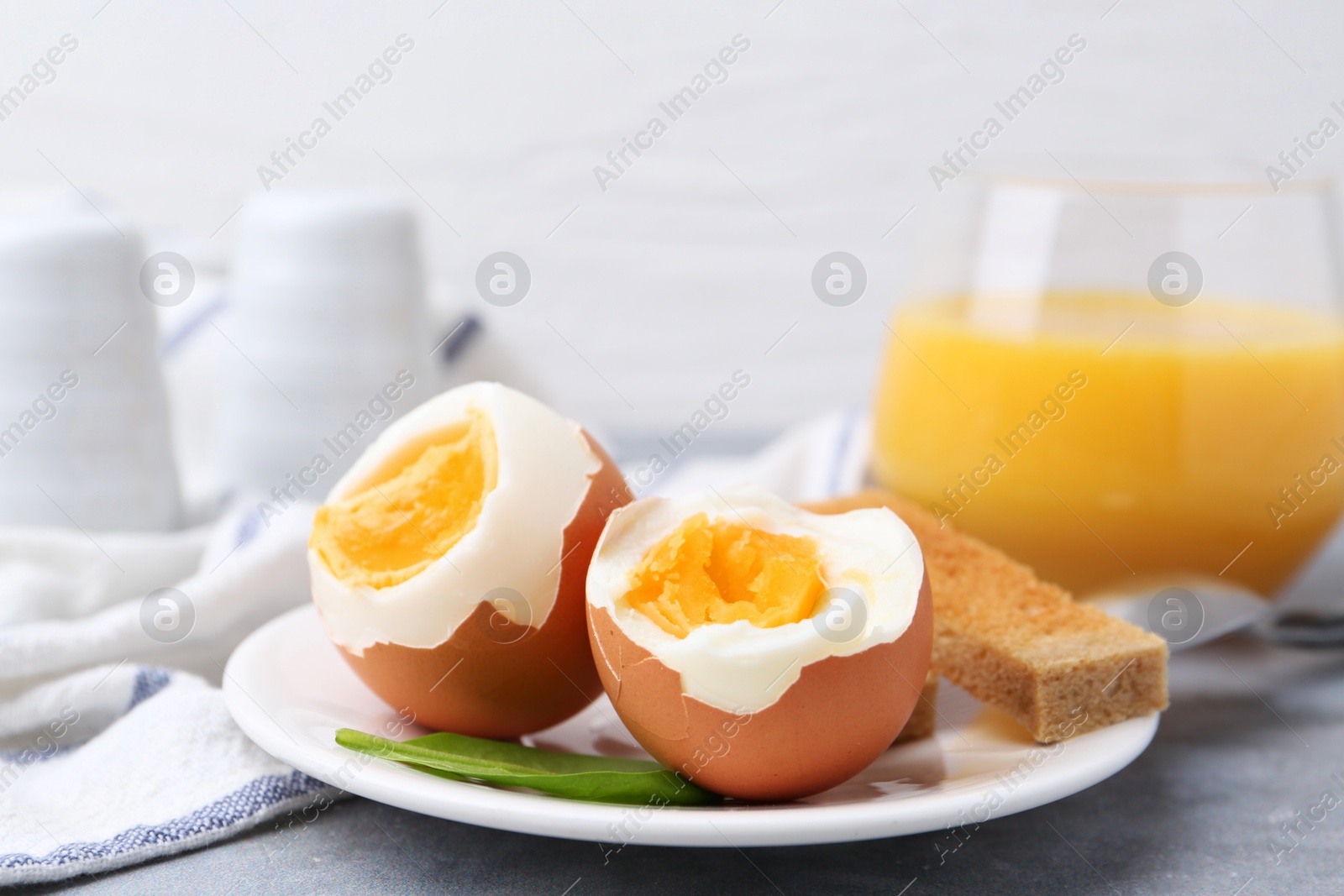 Photo of Soft boiled eggs with bread on grey table, closeup