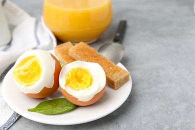 Photo of Soft boiled eggs with bread on grey table, closeup