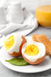 Photo of Soft boiled eggs with bread on grey table, closeup