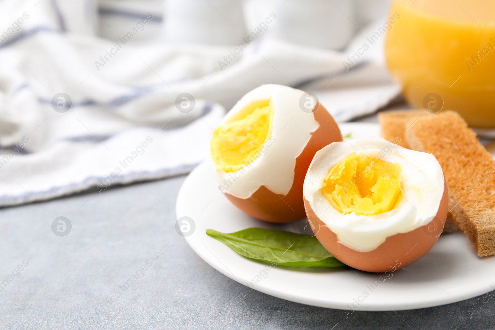 Photo of Soft boiled eggs with bread on grey table, closeup. Space for text