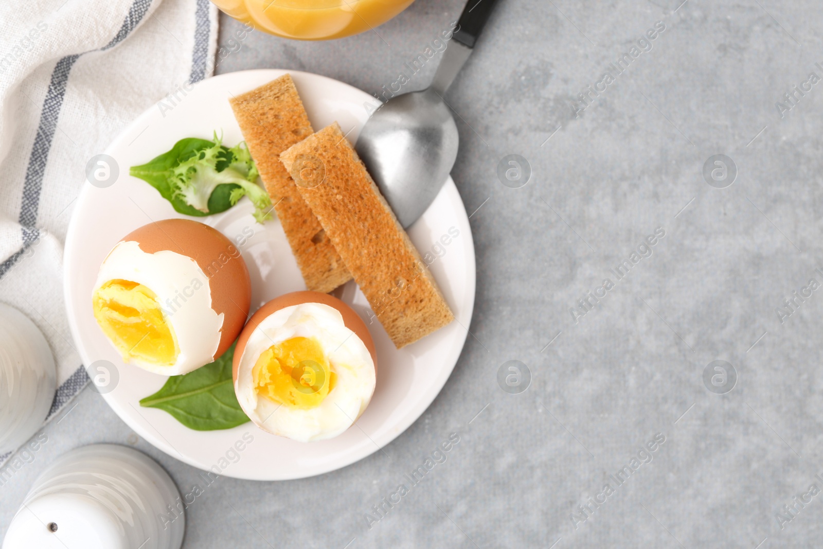 Photo of Soft boiled eggs with bread on grey table, top view. Space for text