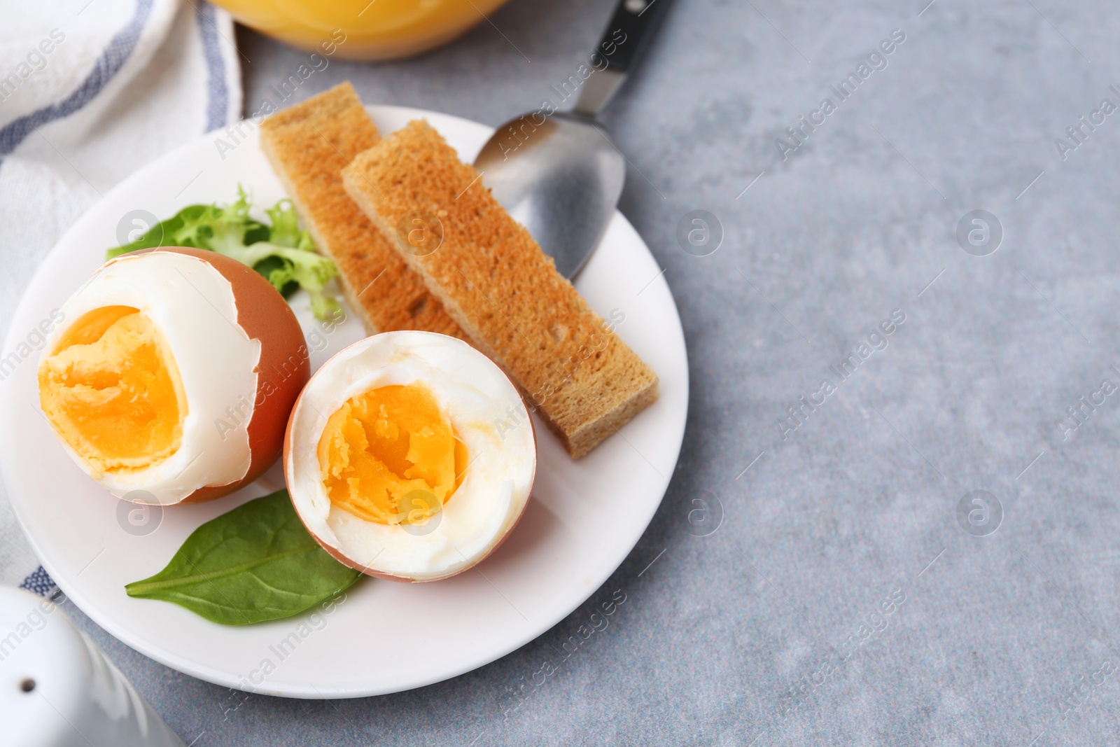 Photo of Soft boiled eggs with bread on grey table, closeup. Space for text