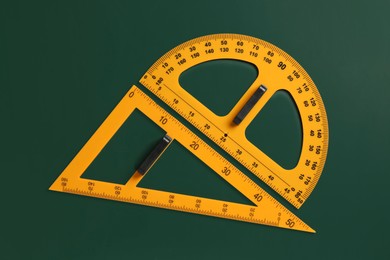 Photo of Protractor and triangle ruler on green chalkboard, top view