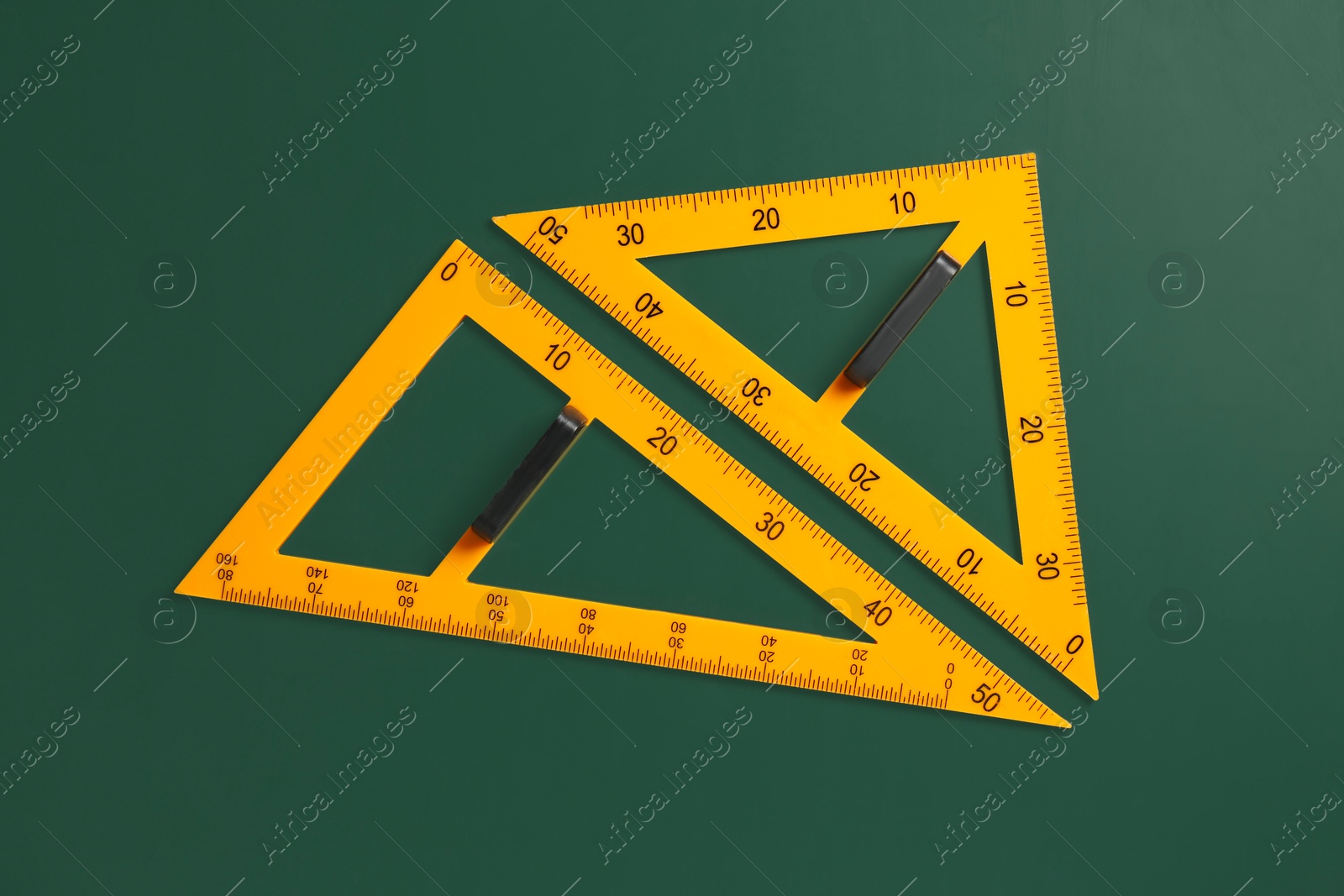 Photo of Triangle rulers on green chalkboard, top view