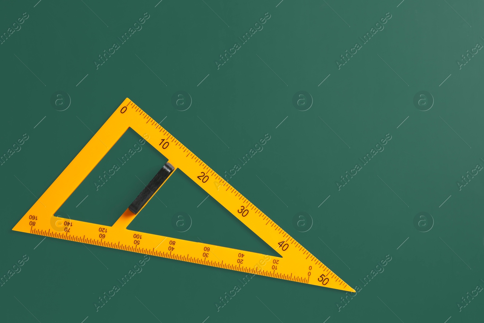 Photo of One triangle ruler on green chalkboard, top view. Space for text