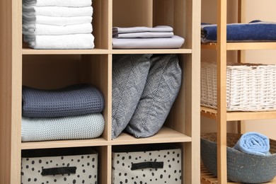 Photo of Different home textile on shelving units indoors, closeup