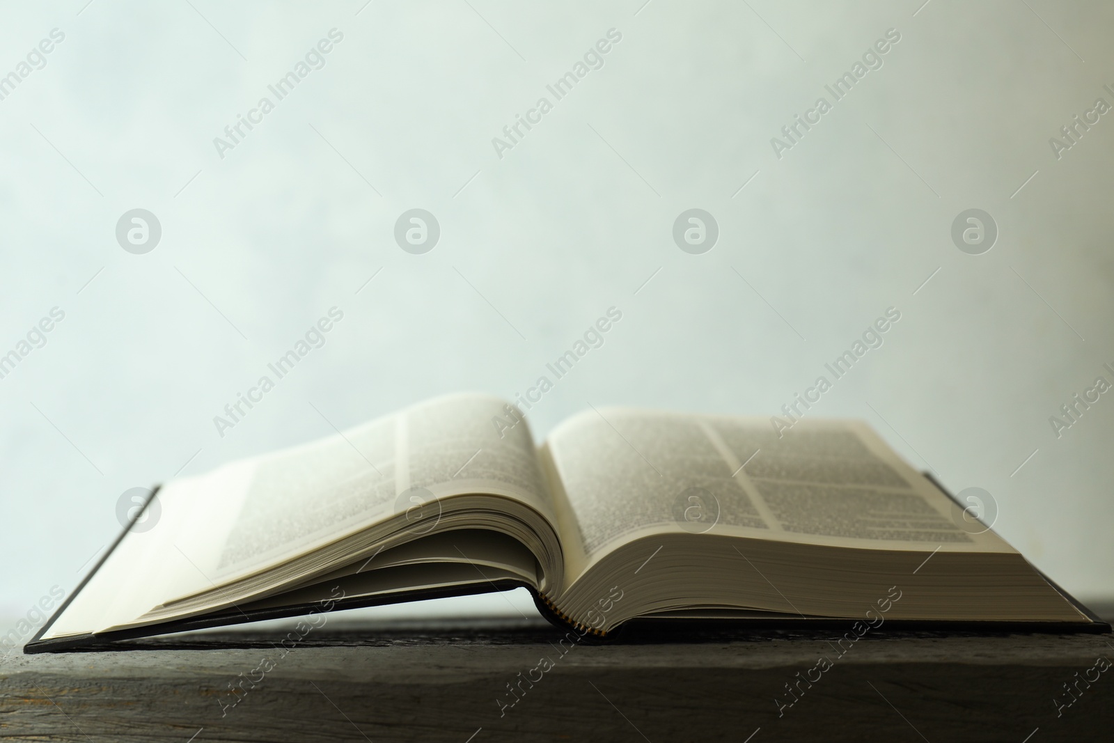 Photo of Open Holy Bible in English language on wooden table. Space for text