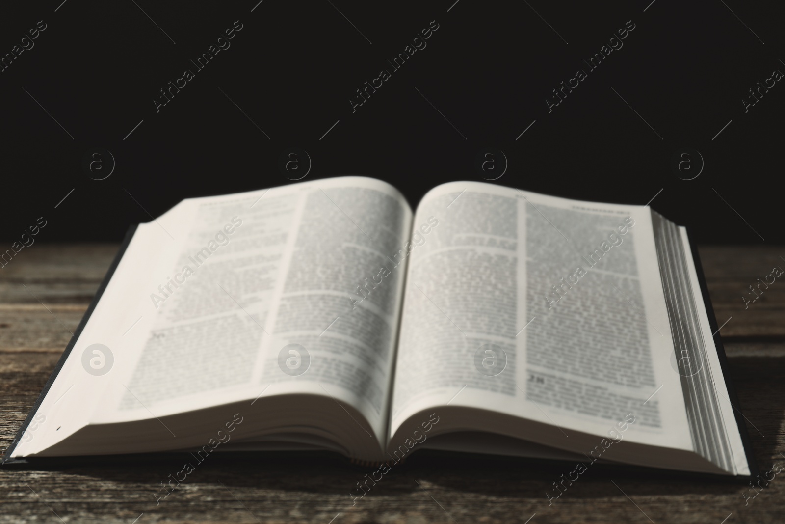 Photo of Open Holy Bible in English language on wooden table