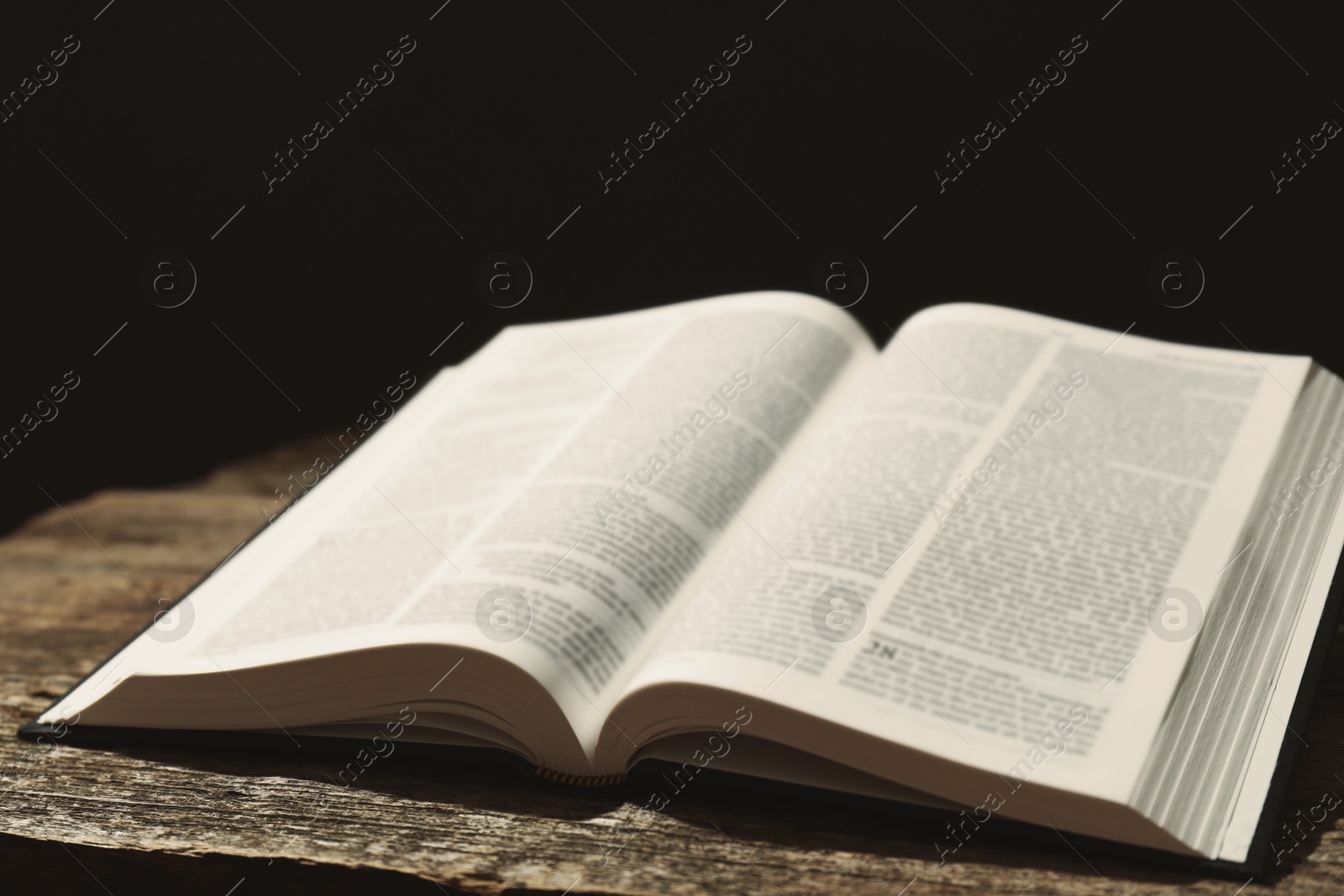 Photo of Open Holy Bible in English language on wooden table