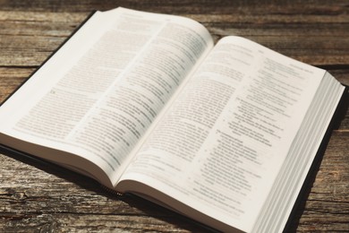 Photo of Open Holy Bible in English language on wooden table, closeup