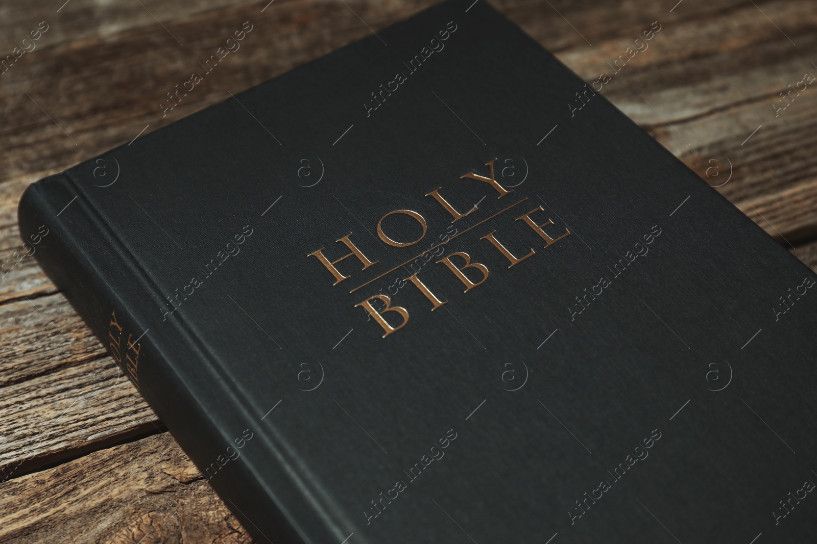 Photo of Hardcover Holy Bible on wooden table, closeup