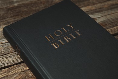 Photo of Hardcover Holy Bible on wooden table, closeup