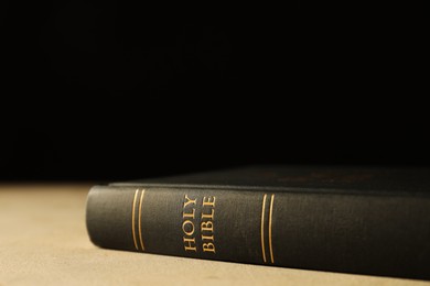 Photo of Hardcover Holy Bible on beige table, closeup