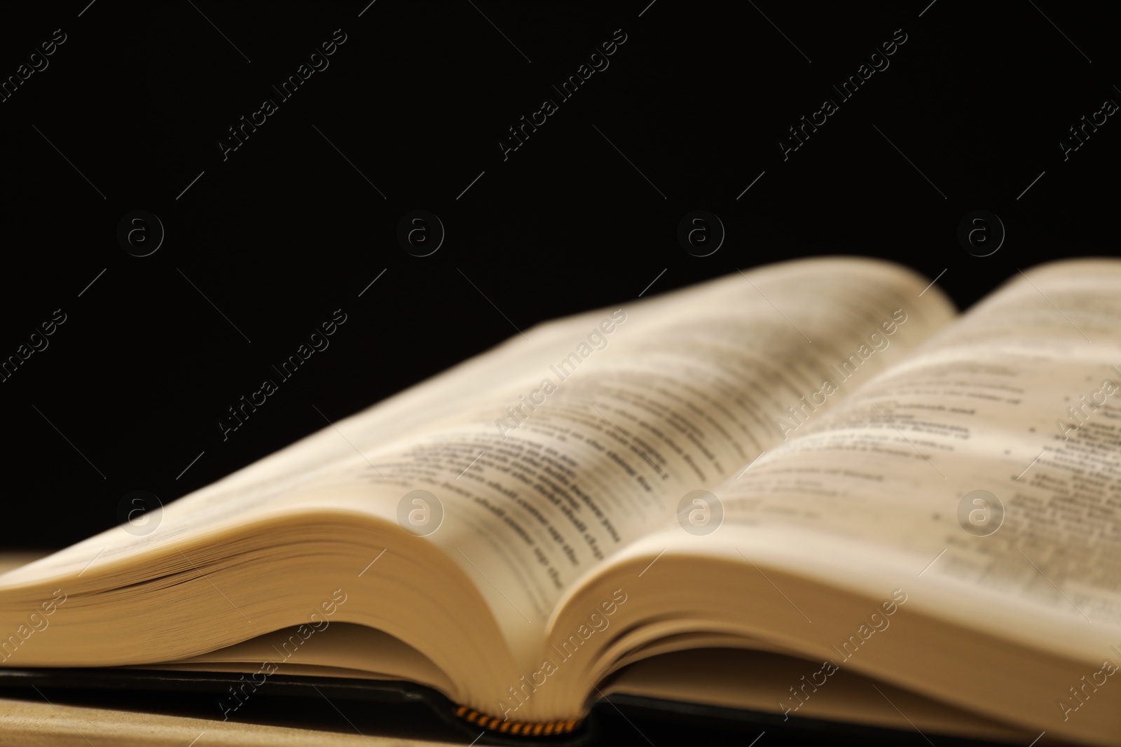 Photo of Open Holy Bible in English language on table, closeup