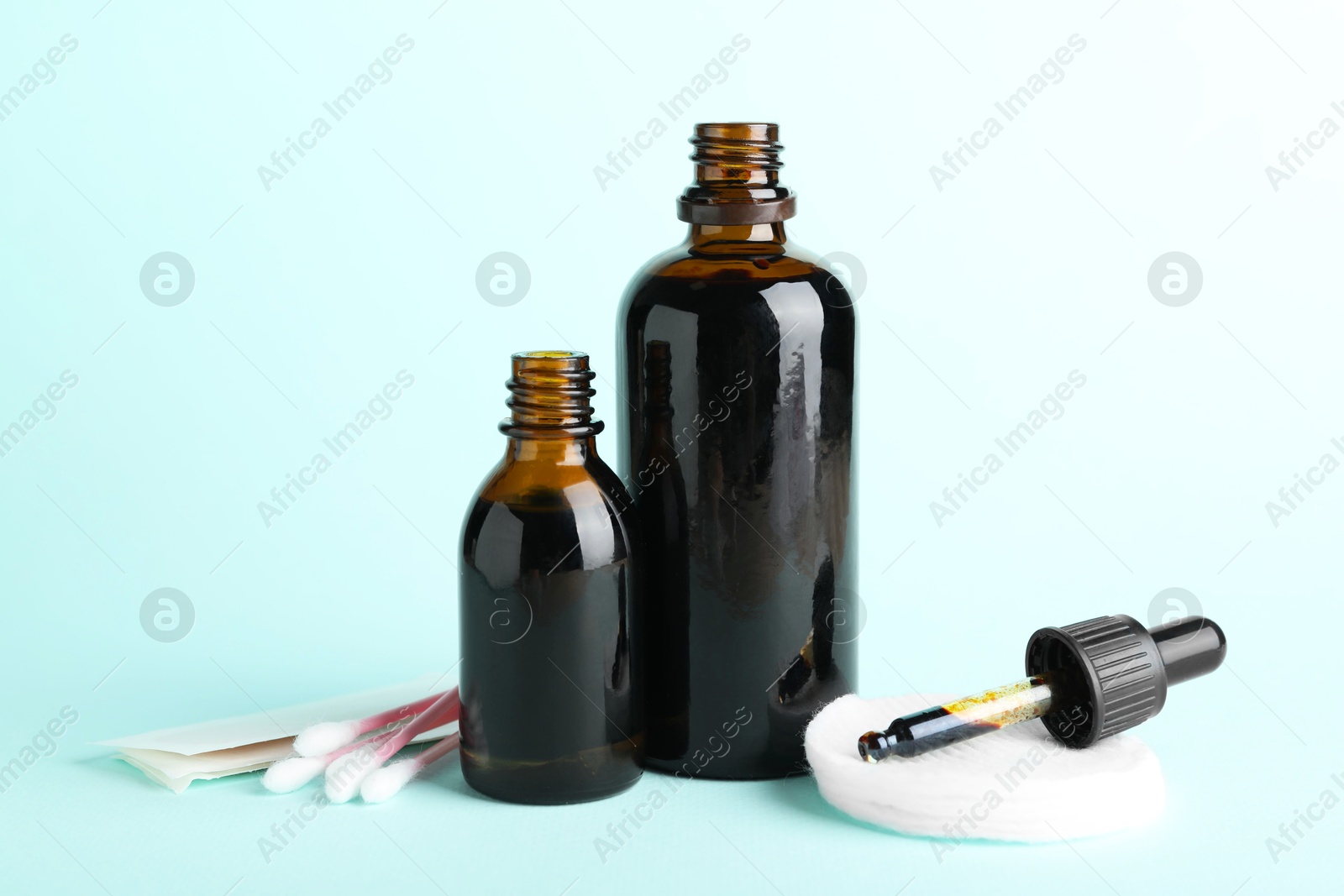 Photo of Topical iodine, cotton pads, swabs and adhesive bandages on light blue background