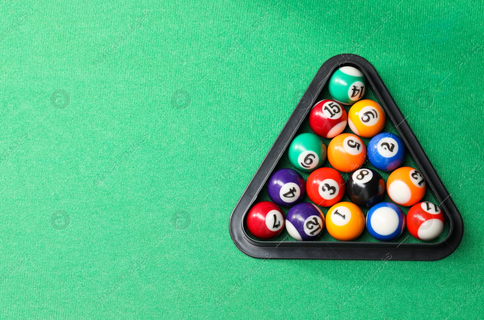 Photo of Billiard balls triangle rack on green table, top view. Space for text