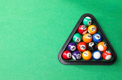 Photo of Billiard balls triangle rack on green table, top view. Space for text