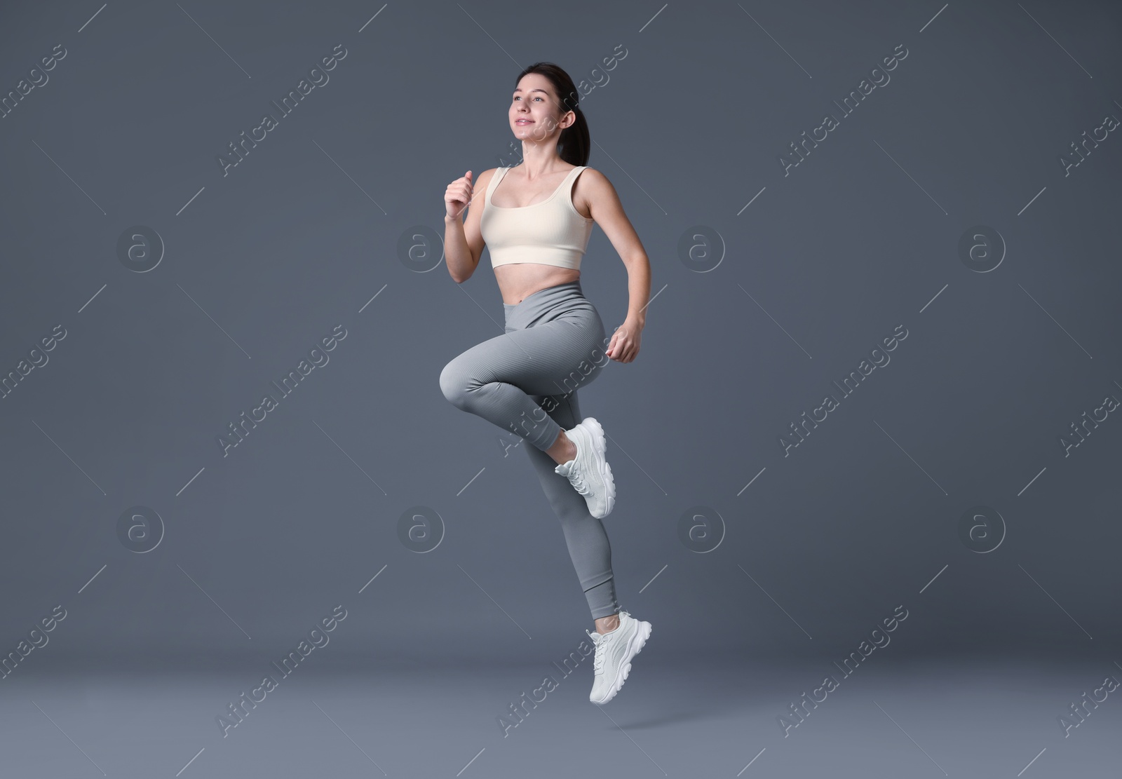 Photo of Woman in sportswear exercising on grey background