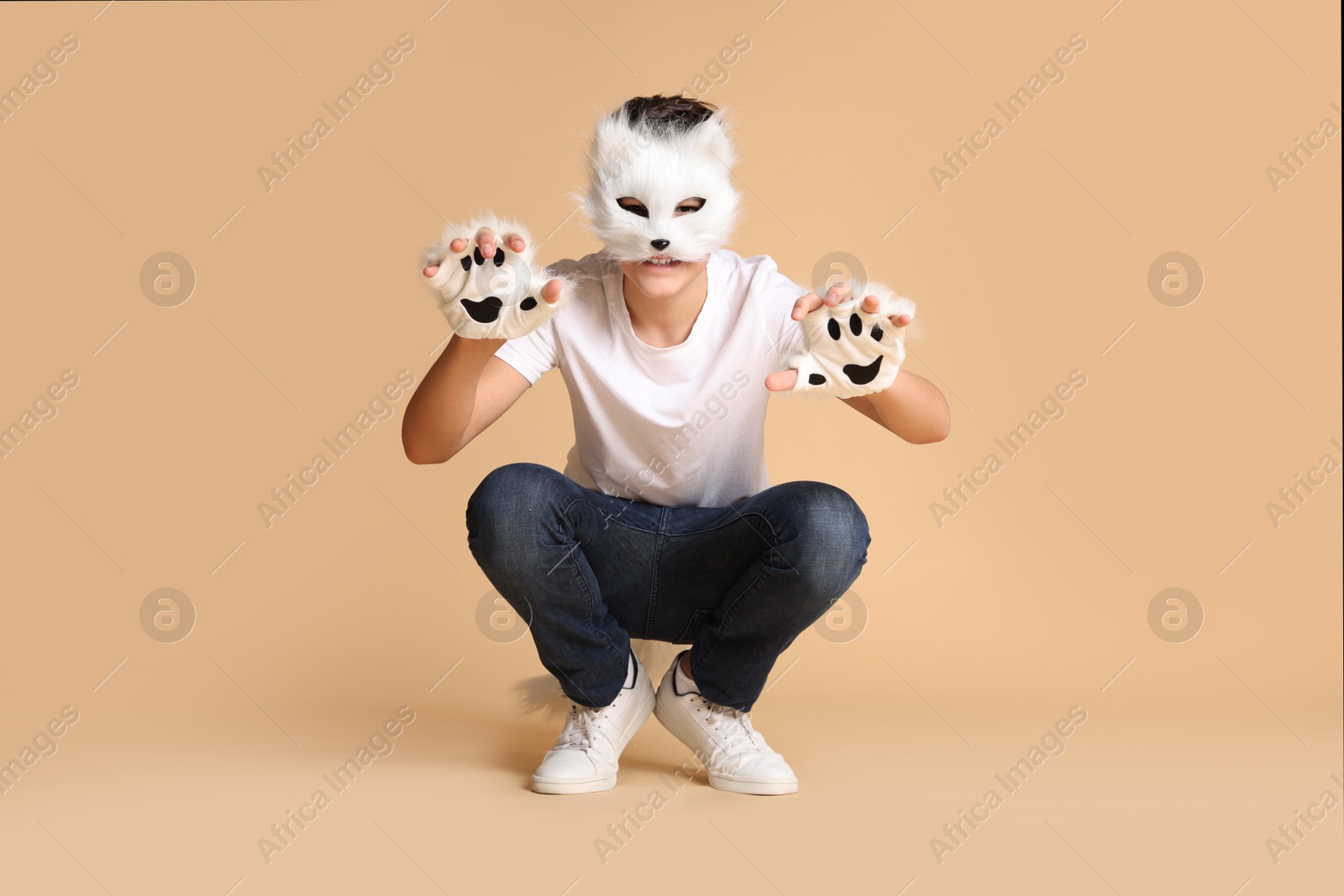 Photo of Quadrobics. Boy wearing cat mask and gloves on beige background