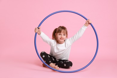 Photo of Cute little girl with hula hoop on pink background