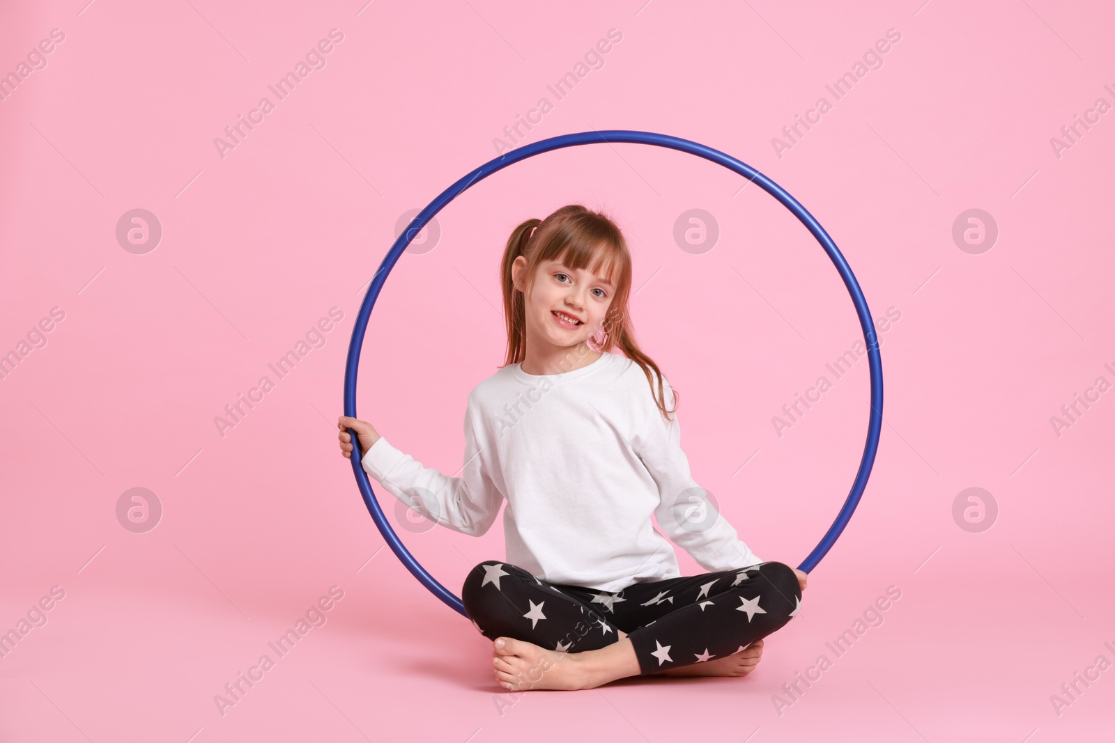 Photo of Cute little girl with hula hoop on pink background