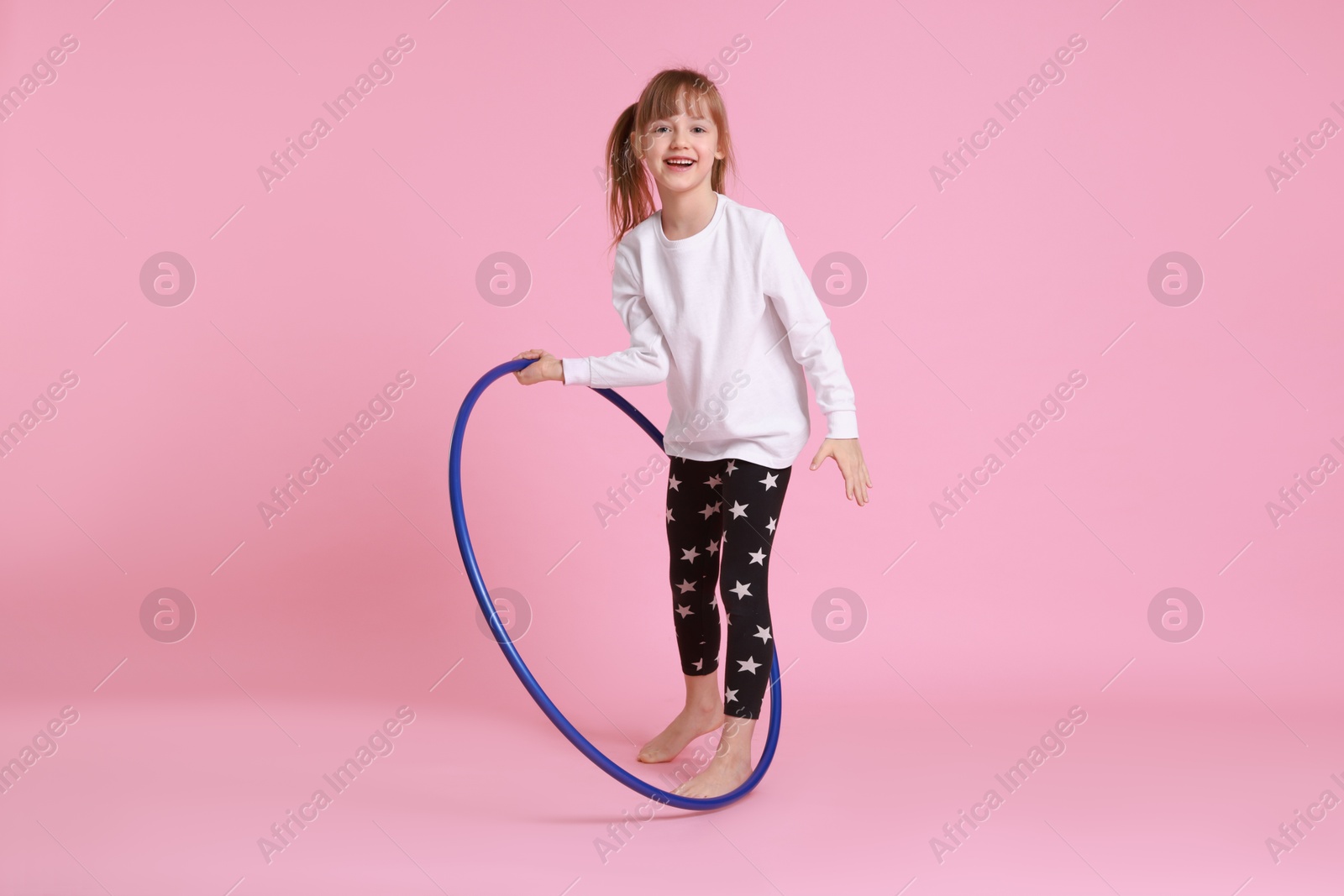 Photo of Cute little girl with hula hoop on pink background