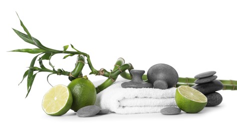 Photo of Spa composition with limes, massage stones, towel and bamboo stems isolated on white