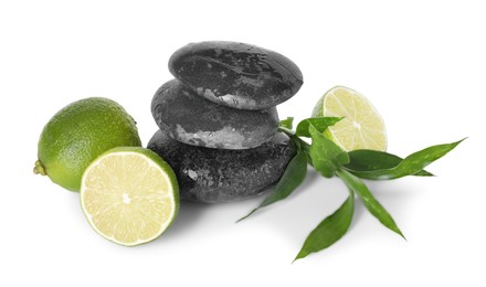Photo of Spa composition with limes, massage stones and green leaves isolated on white