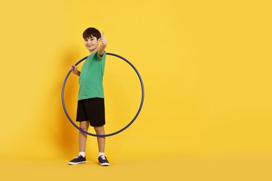 Photo of Boy with hula hoop showing thumbs up on yellow background, space for text