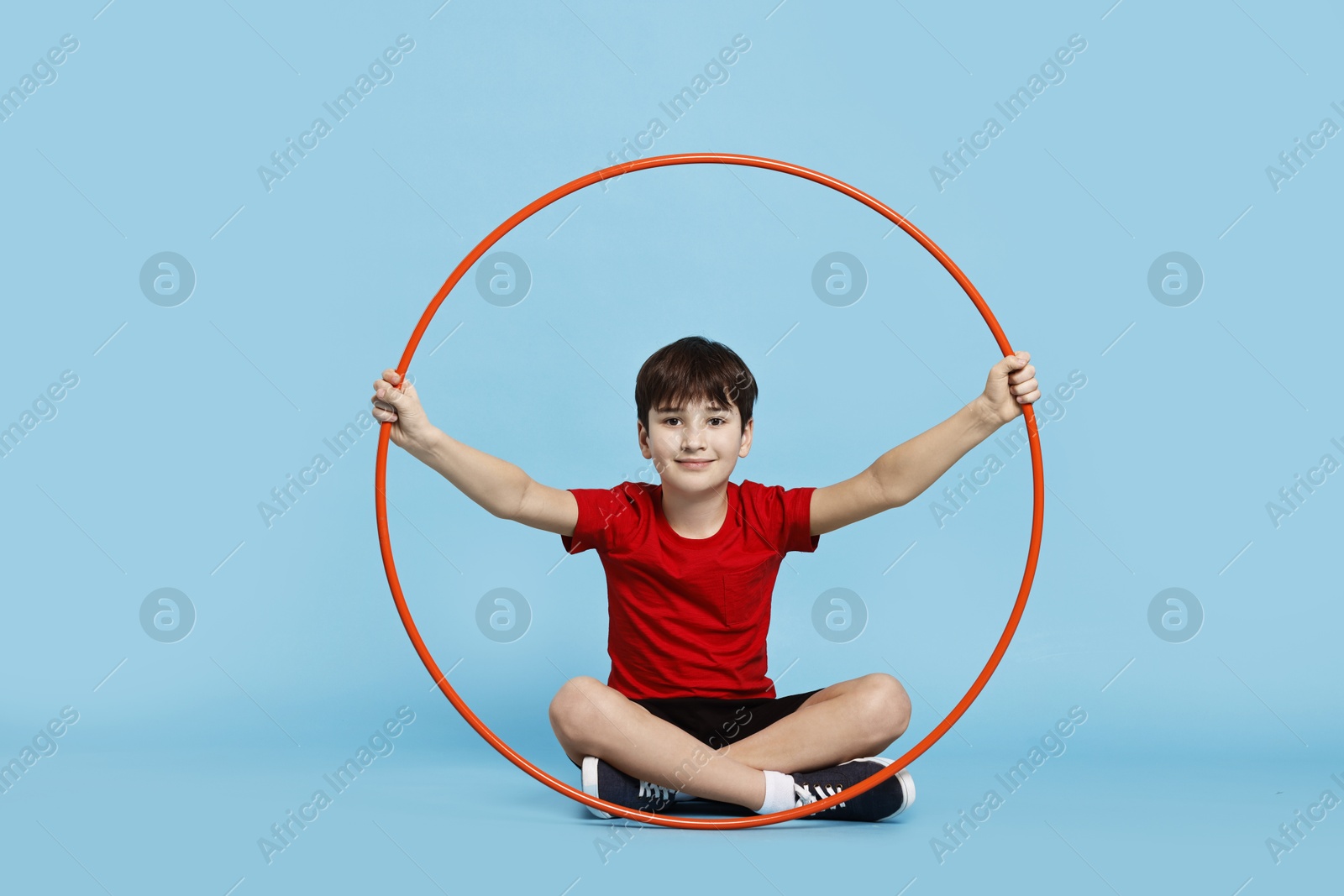 Photo of Boy with hula hoop on light blue background