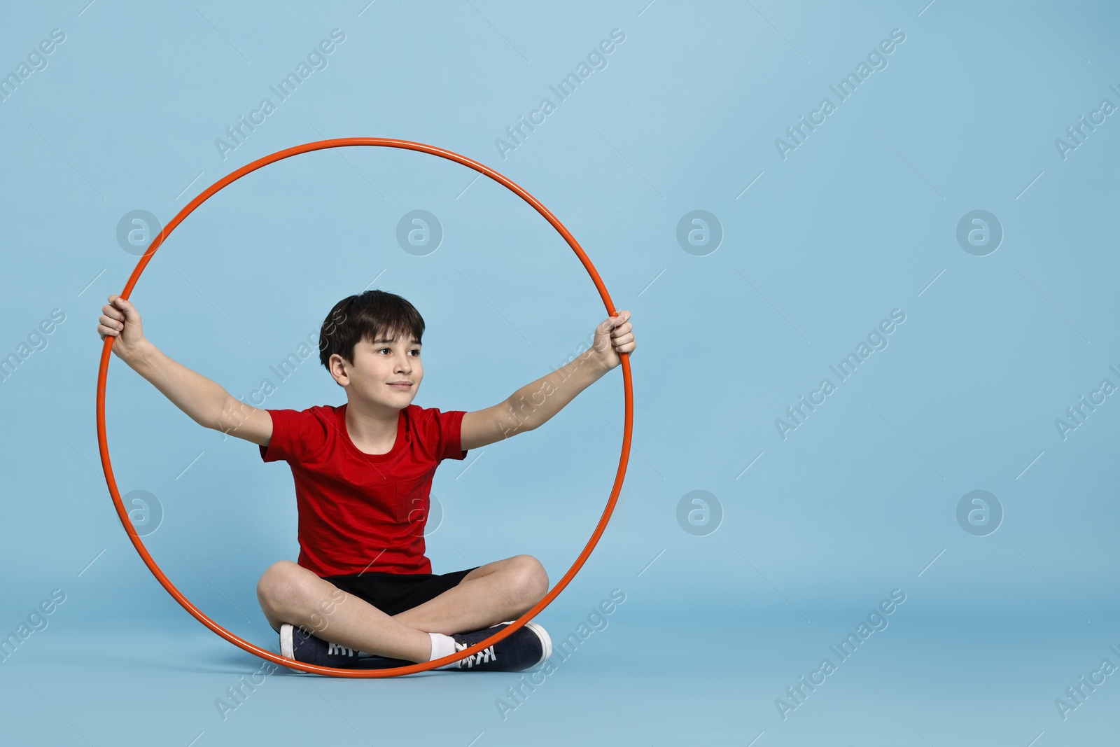 Photo of Boy with hula hoop on light blue background, space for text