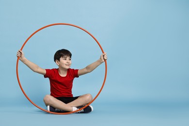 Photo of Boy with hula hoop on light blue background, space for text